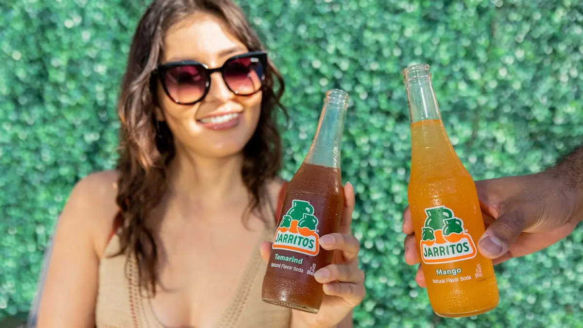 Mujer sonriente mostrando dos botellas de bebida de su emprendimiento
