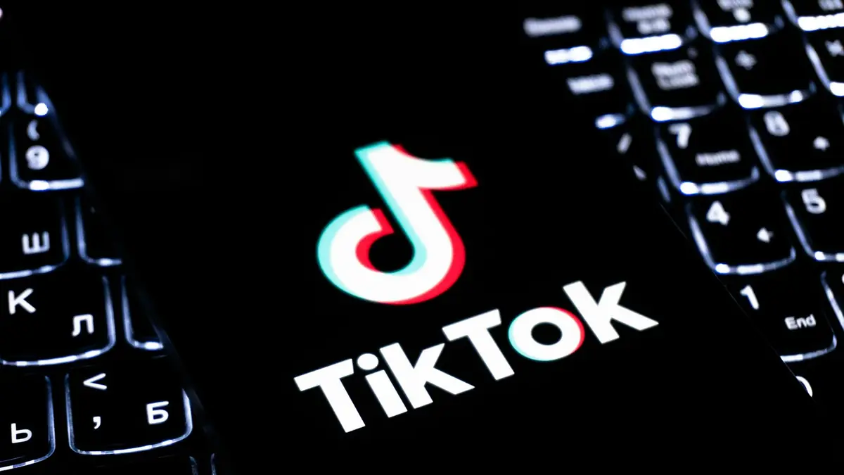 Logo de TikTok en una pantalla junto a un teclado iluminado