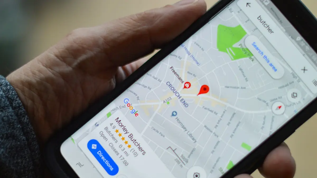 Mano sosteniendo un teléfono con Google Maps y la ficha de un negocio local