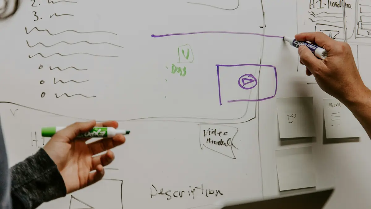 Dos personas dibujando un diagrama de proceso en una pizarra