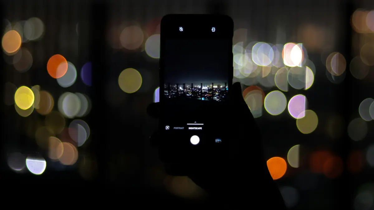 Teléfono inteligente con luces de la ciudad de noche al fondo
