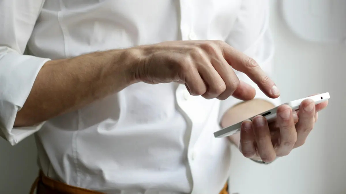 Persona sosteniendo un teléfono inteligente con la pantalla encendida