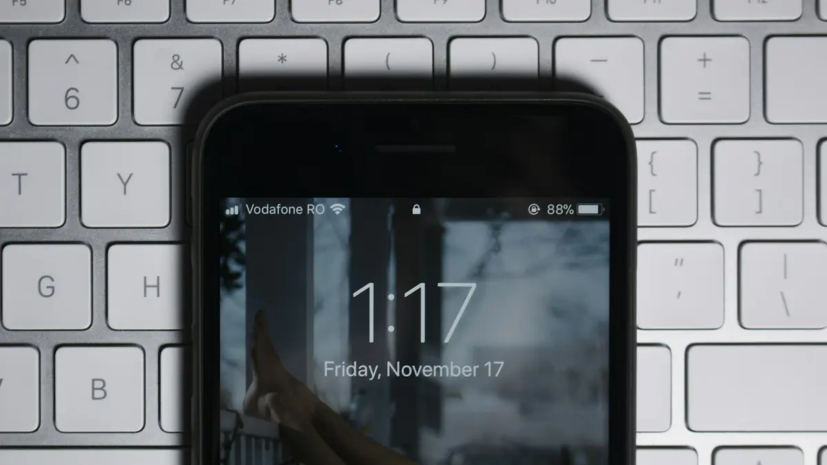 Celular con la pantalla de bloqueo encendida sobre un teclado blanco