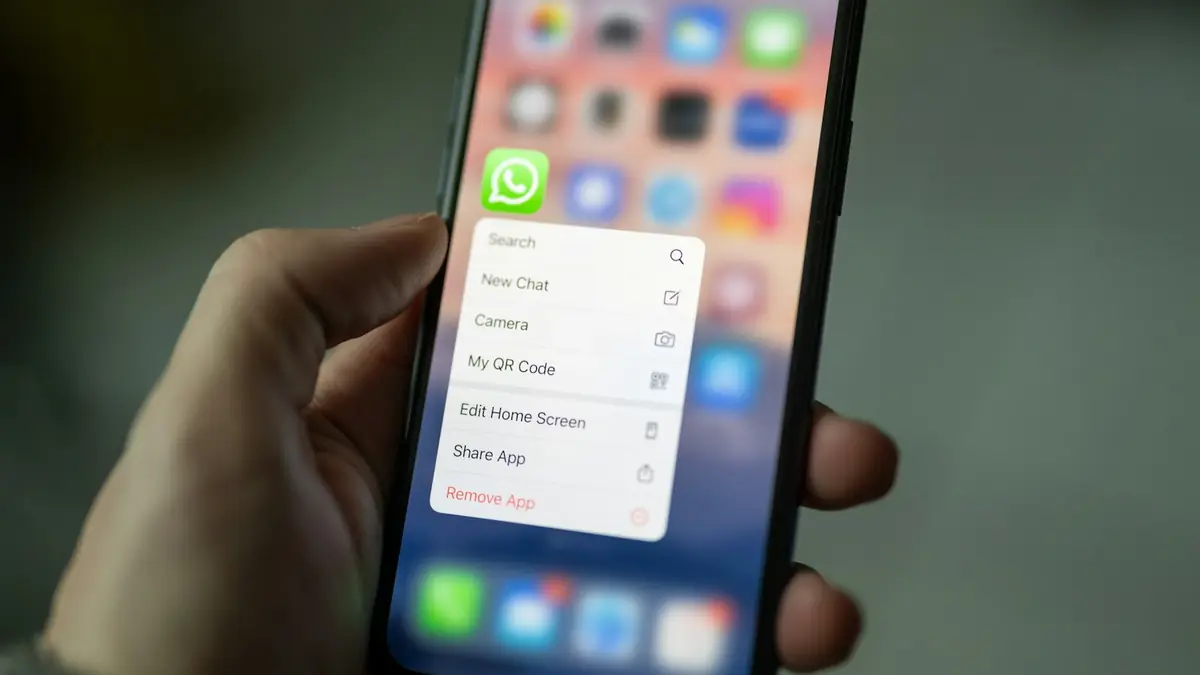 Mano sosteniendo un teléfono con la aplicación de WhatsApp en pantalla