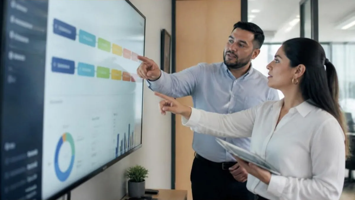 Supervisor y vendedora latinos revisando las etapas del embudo en una pantalla